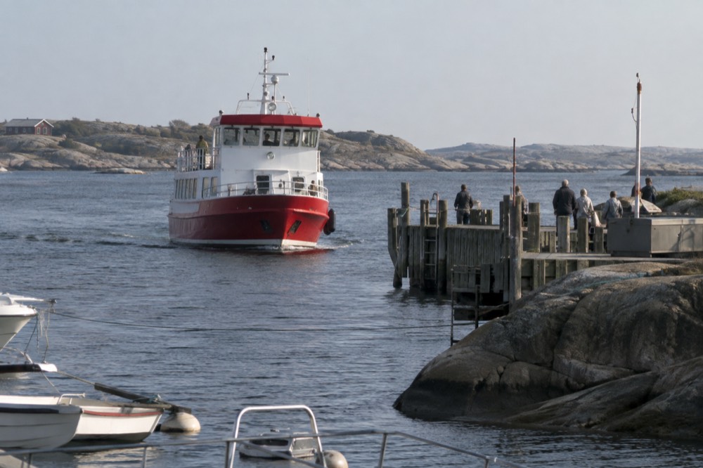 Red archipelago ferry approaching a wooden jetty on a small car-free Swedish island