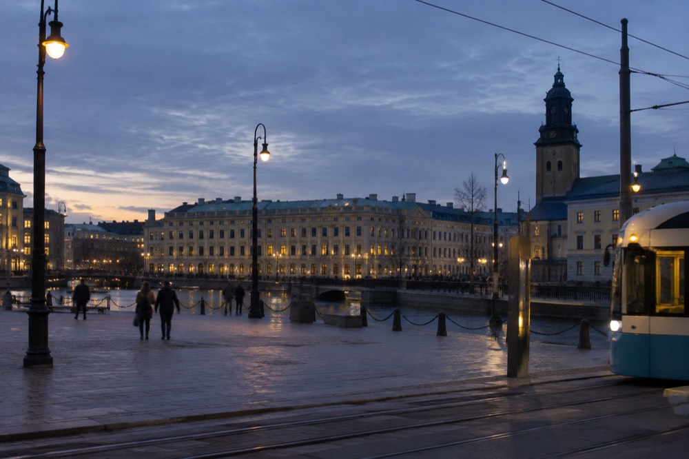 A Swedish regional train at a platform beside a station clock in evening light