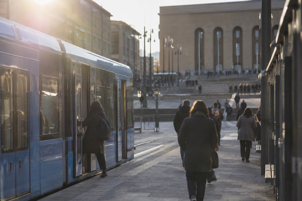 A passenger boarding a blue tram through the middle doors at a stop near Avenyn