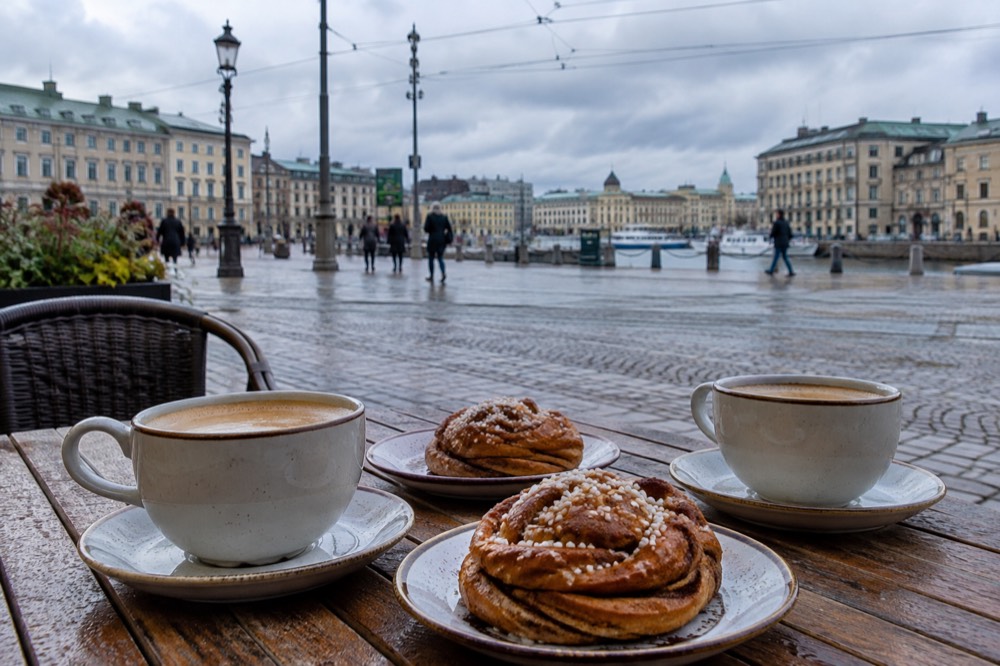 Two coffee cups and cinnamon buns on a wooden cafe table in Gothenburg