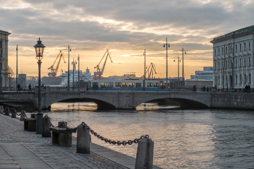 A Gothenburg tram crossing a granite bridge near the city centre with harbour cranes behind