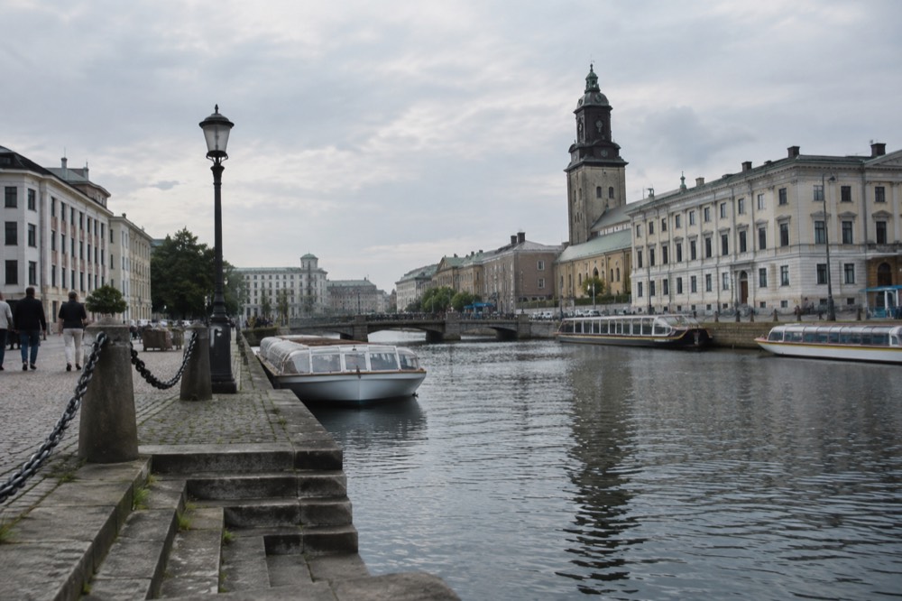 Gothenburg canal with sightseeing boats and painted wooden buildings under a grey sky