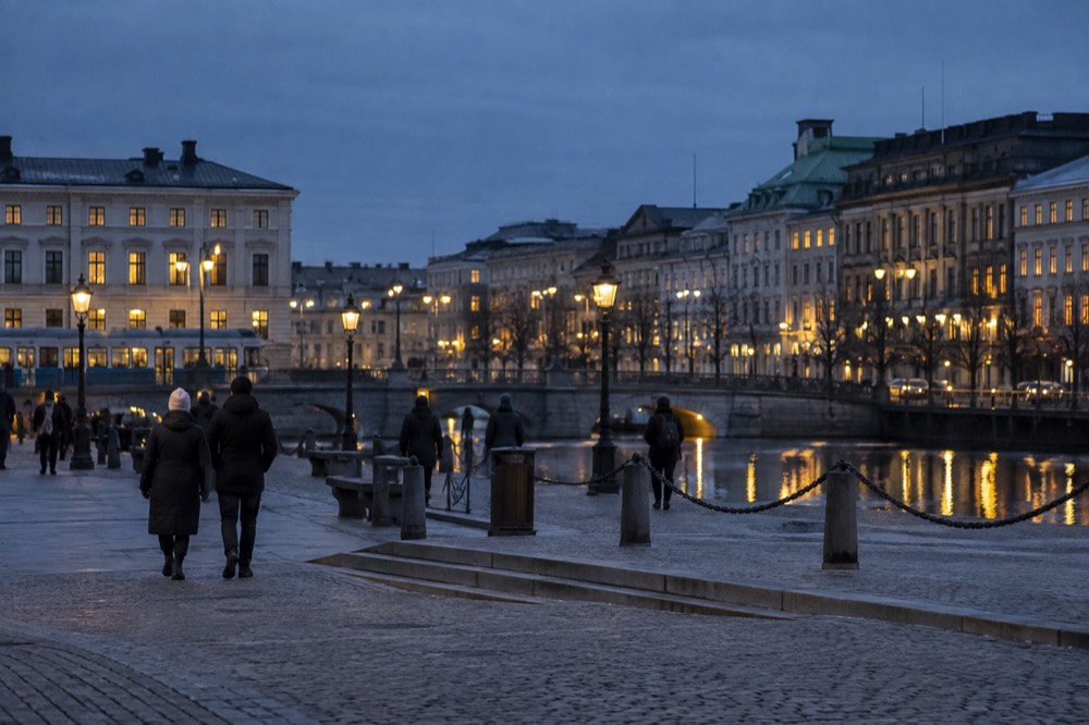 Winter afternoon in Gothenburg with street lamps lit against a dark blue sky over a canal
