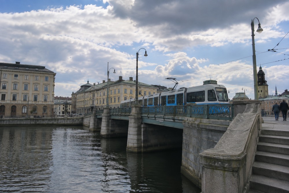 A blue Gothenburg tram crossing a city bridge on a bright morning