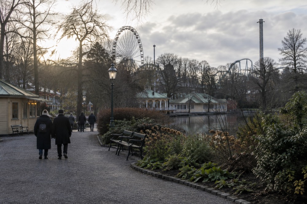 Amusement park entrance plaza with a large ferris wheel rising above the treetops