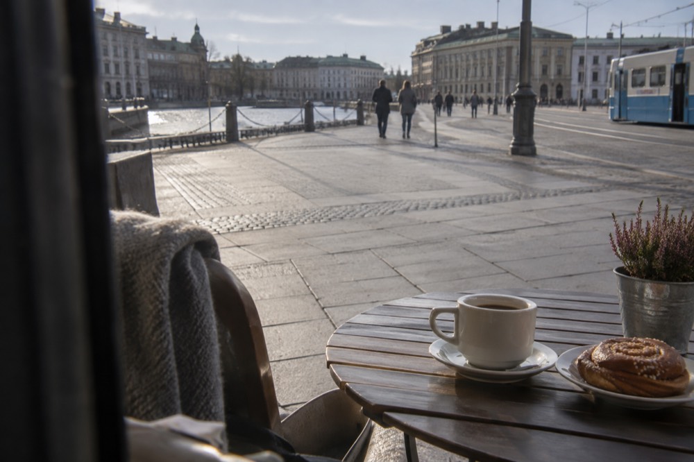 A cup of coffee and a cinnamon bun on a wooden cafe table in Gothenburg