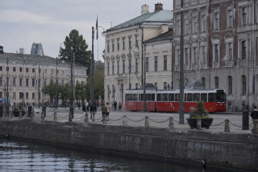 Red Gothenburg tram on a granite-paved street with brick buildings under grey sky