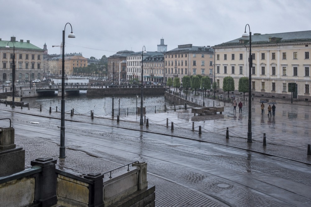 Wet cobblestone street in Gothenburg old town with rain-slicked paving and grey sky over old brick warehouses