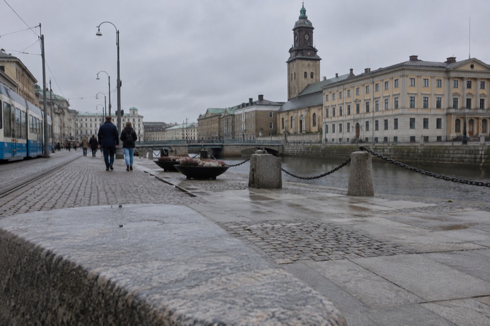 A stone-paved street in central Gothenburg with painted wooden houses and a tram line running alongside