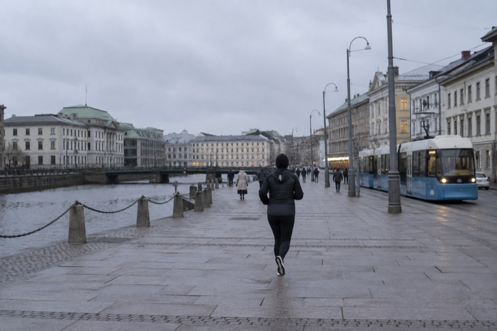 A Gothenburg tram moving down a granite-edged street with painted wooden buildings on a grey day