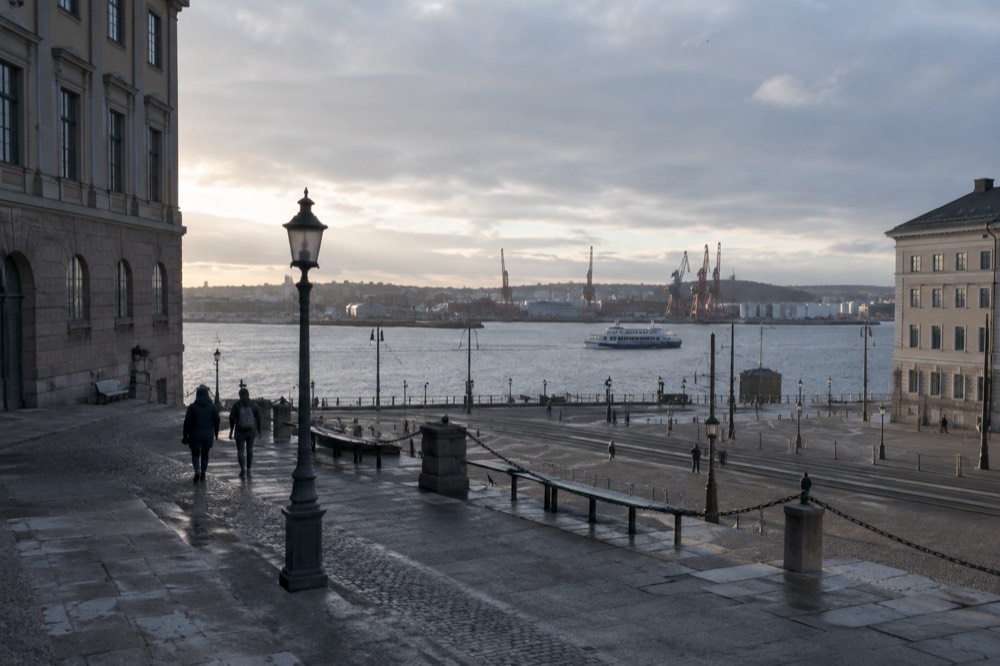 Gothenburg rooftops and harbour cranes seen from a hill above the city, with the Göta älv running toward the sea