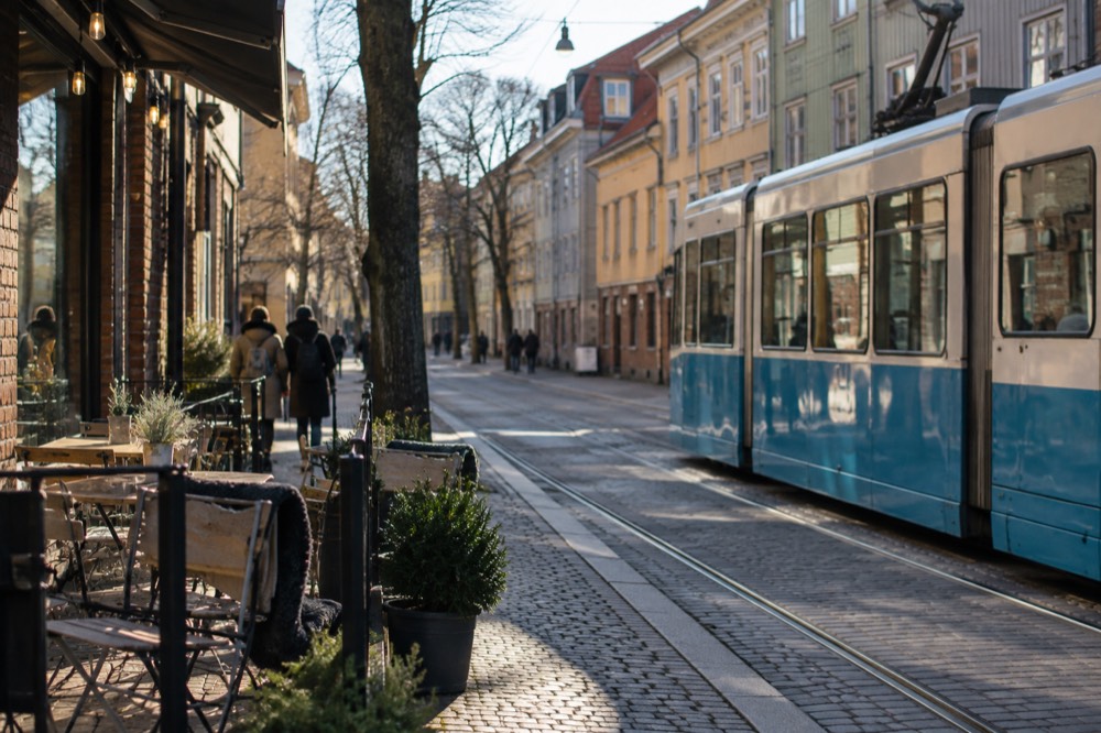 A Gothenburg tram passing painted wooden houses in the Haga district on a bright afternoon