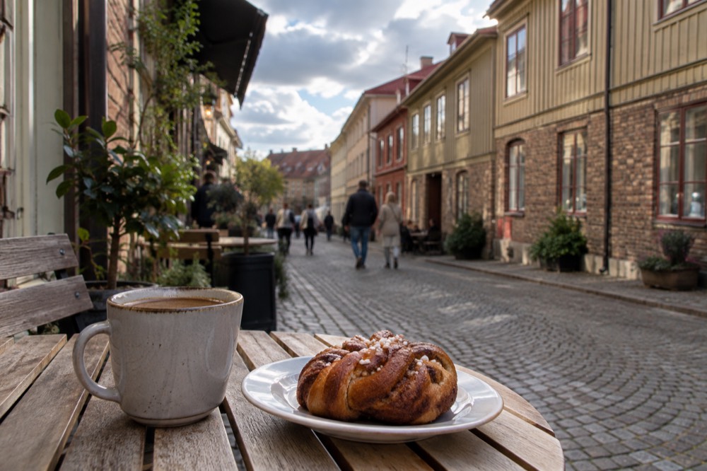 A cinnamon bun and coffee on a wooden cafe table in Haga, Gothenburg