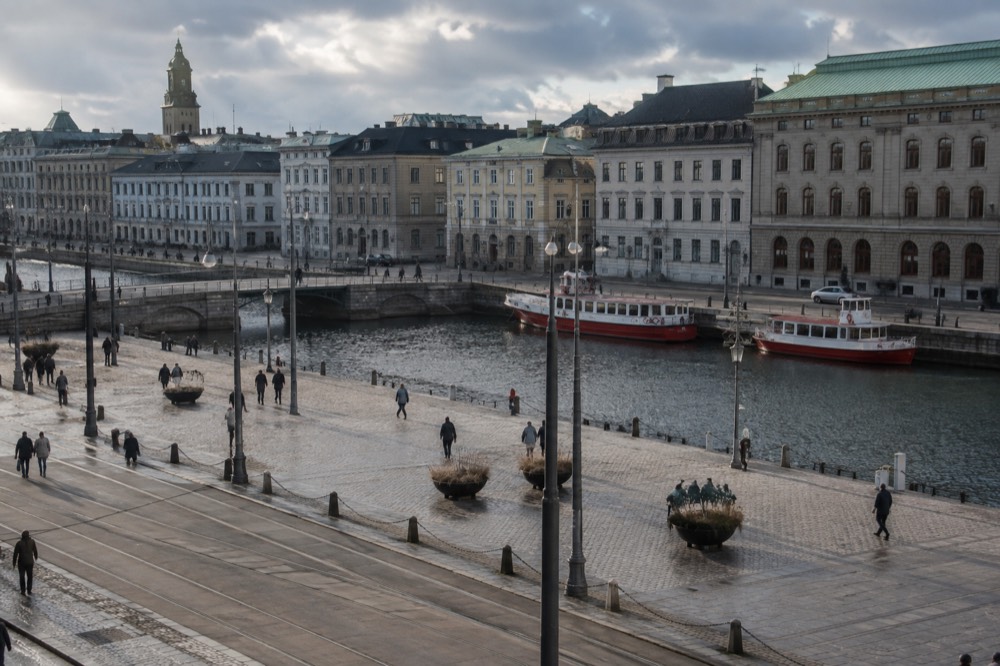 Red wooden boats moored in a Gothenburg canal under a grey Nordic sky, with stone buildings behind them