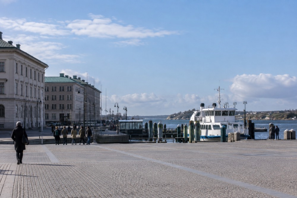 A white archipelago ferry at a wooden jetty with granite islands and open sea behind it