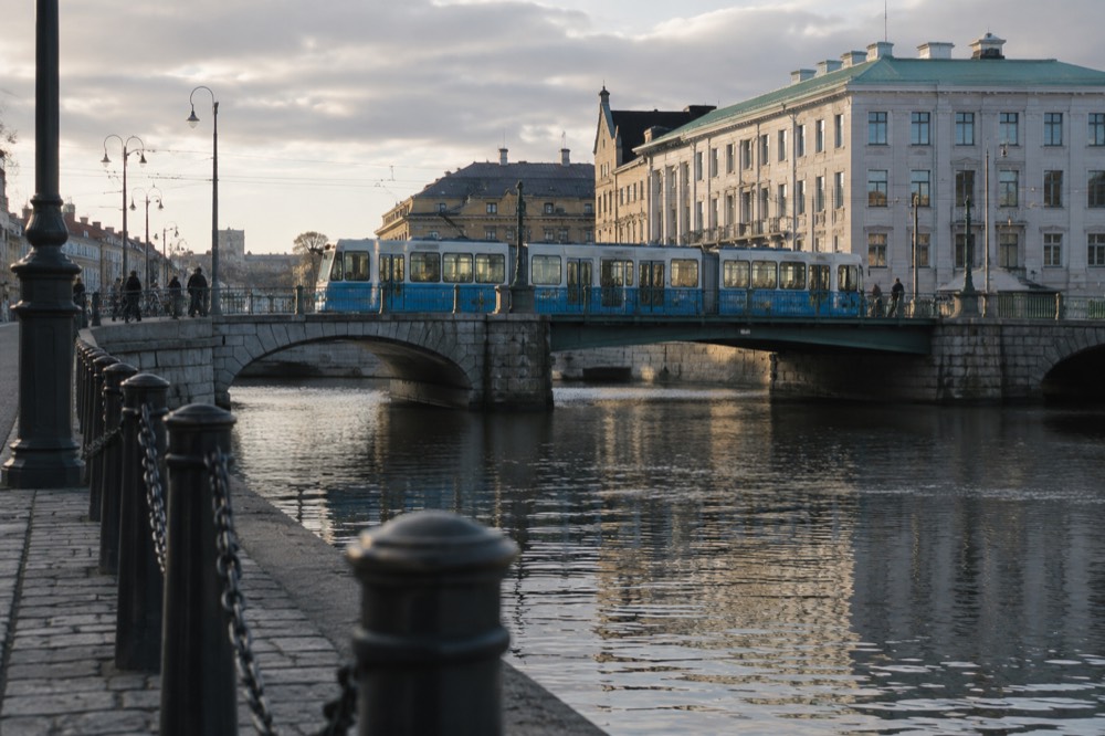A blue Gothenburg tram crossing a stone bridge over a canal in the city centre