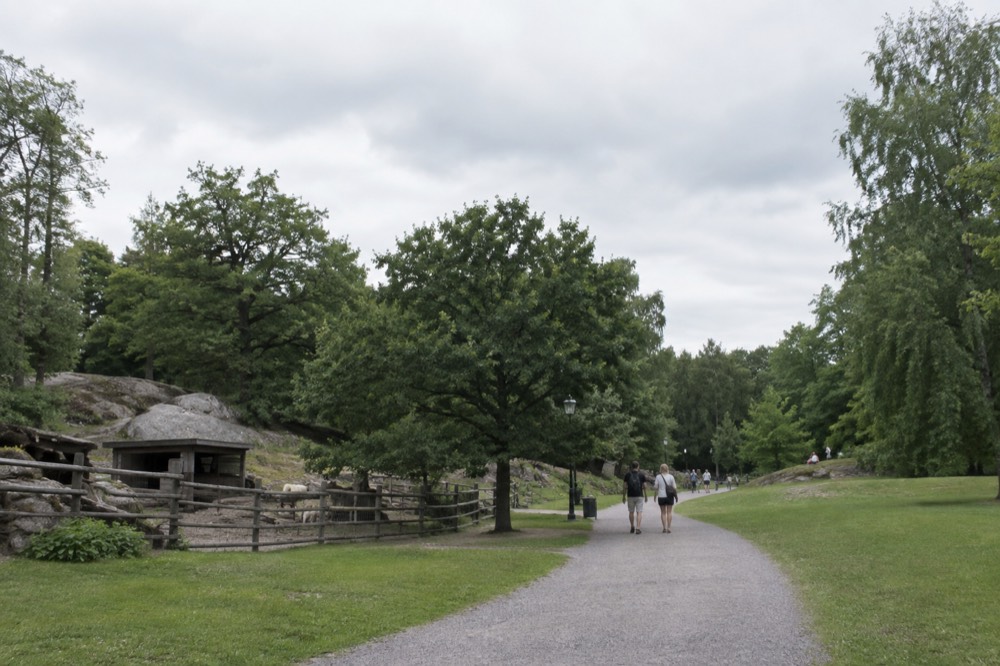 Visitors walking a gravel path through Slottsskogen park with lawns and trees in summer