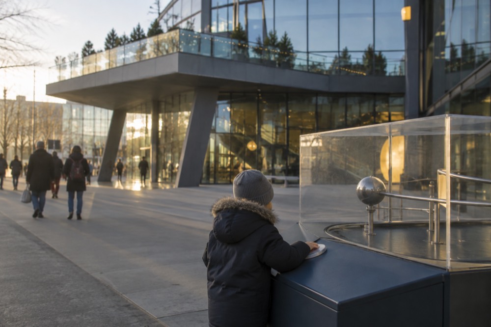 A child pressing a button on a hands-on science exhibit in a bright exhibition hall