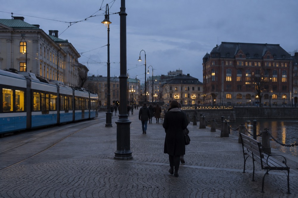 A Gothenburg tram on a granite-paved street with red brick buildings under grey sea light