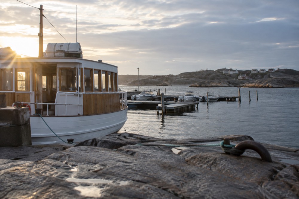 A wooden archipelago ferry at Saltholmen quay with island cottages beyond