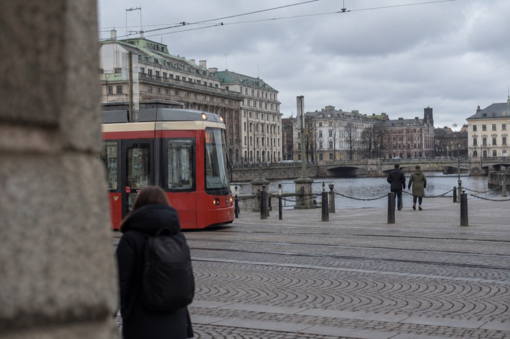 Red tram on a granite street in central Gothenburg with a canal and old brick buildings behind it