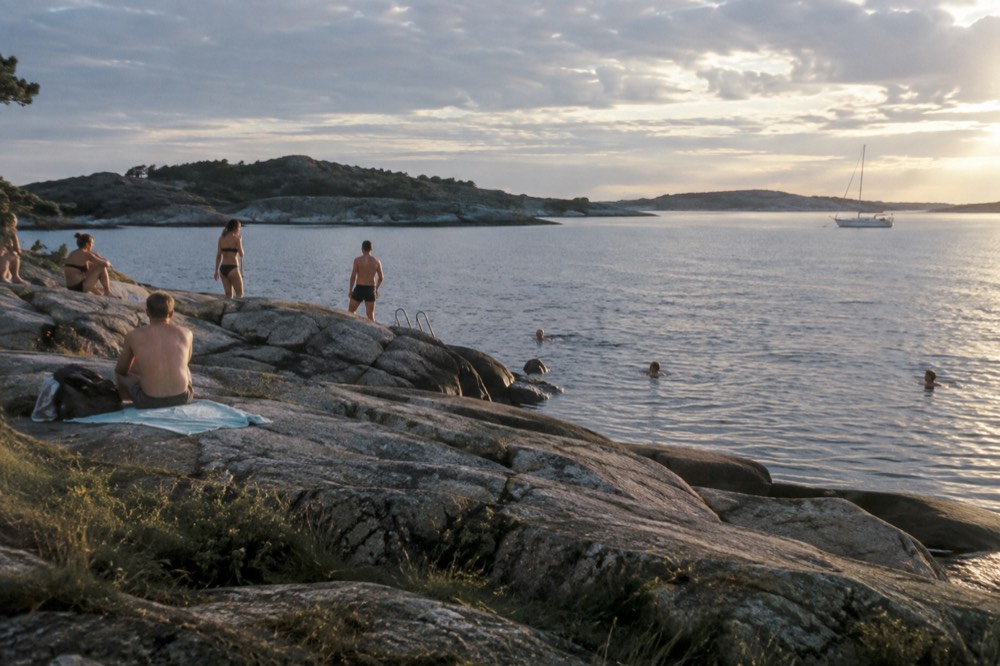 Bathers on a rocky island shore in the Gothenburg archipelago on a calm summer evening