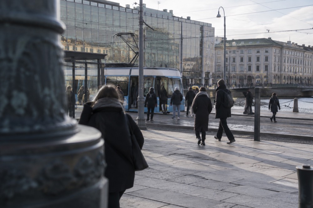 A blue Gothenburg tram at a busy interchange stop outside a modern glass museum building