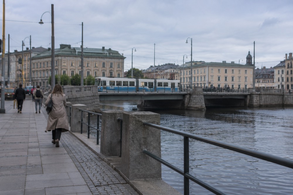 A tram passing a canal in central Gothenburg, granite embankment and overhead wires