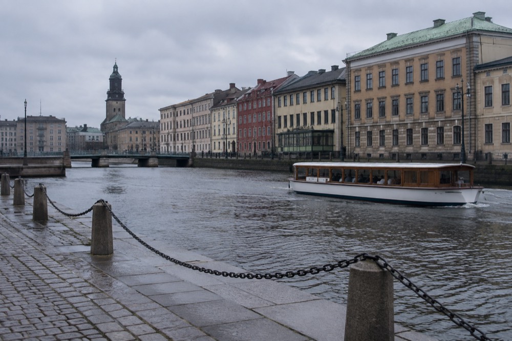 A canal boat passing wooden buildings in central Gothenburg, Sweden