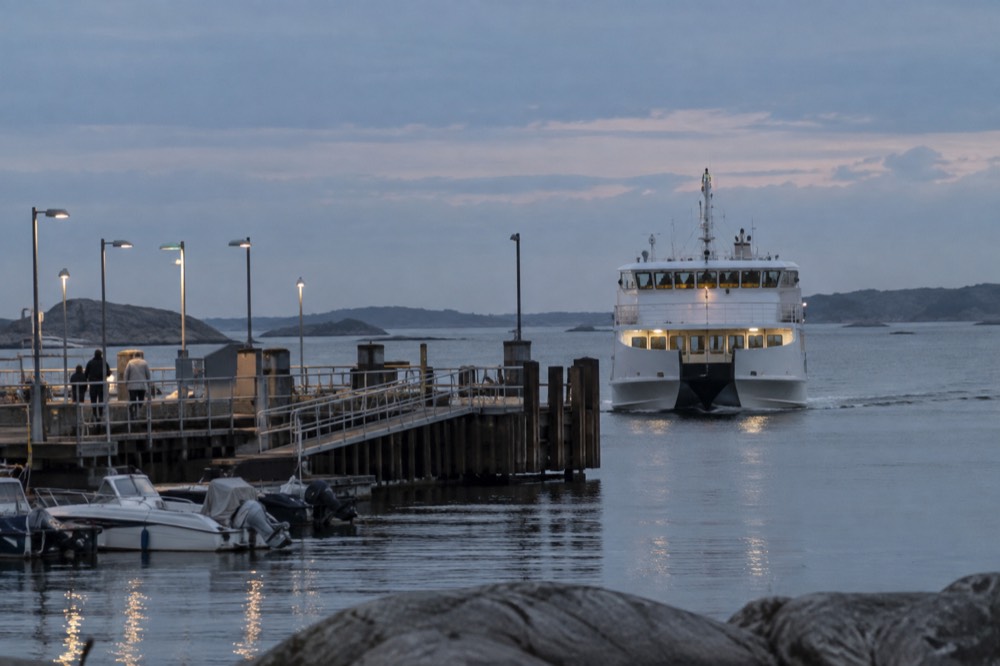 A white archipelago ferry approaching a wooden pier at Saltholmen on a calm grey sea day