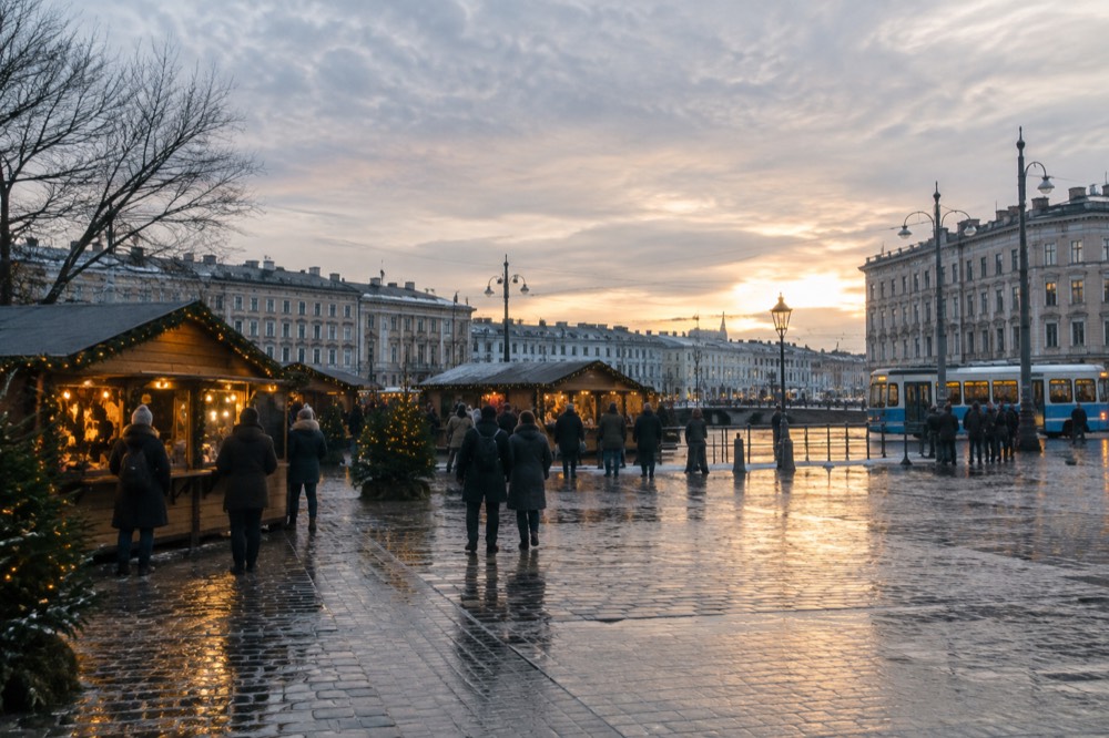 Wooden Christmas stalls with warm lights reflected in wet cobblestones in a Swedish town square