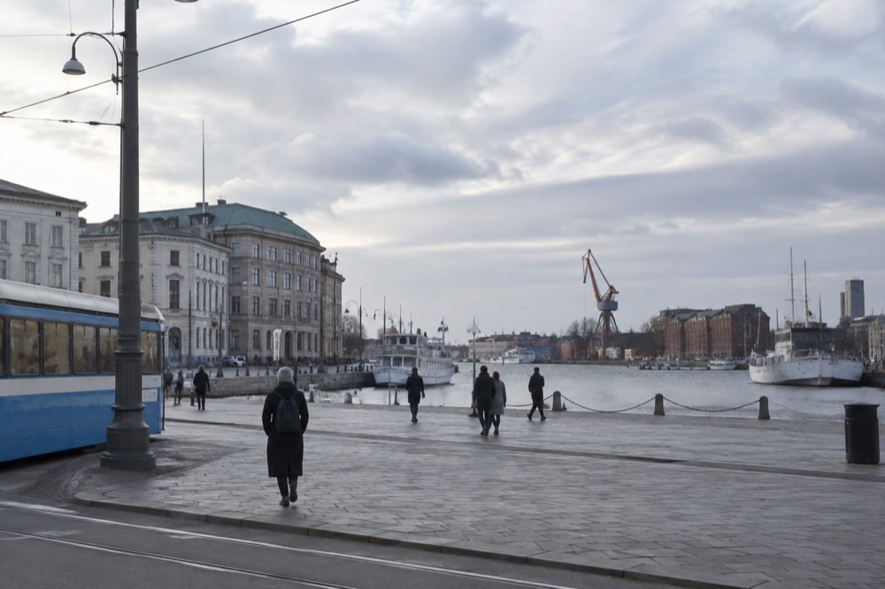 Gothenburg harbour with red brick warehouses, moored boats and a shipyard crane under grey sky