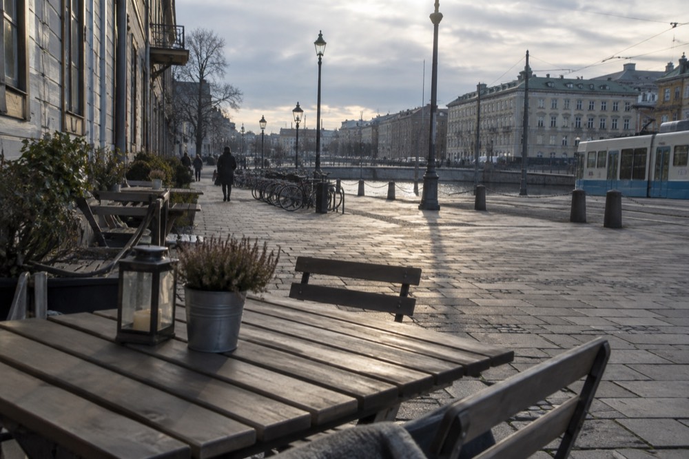Painted wooden houses on a stone street in Gothenburg with a cafe and bicycles