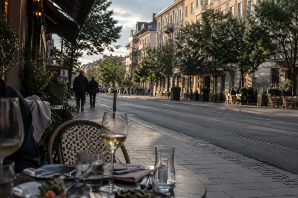 An outdoor restaurant table with glasses and small plates in evening light