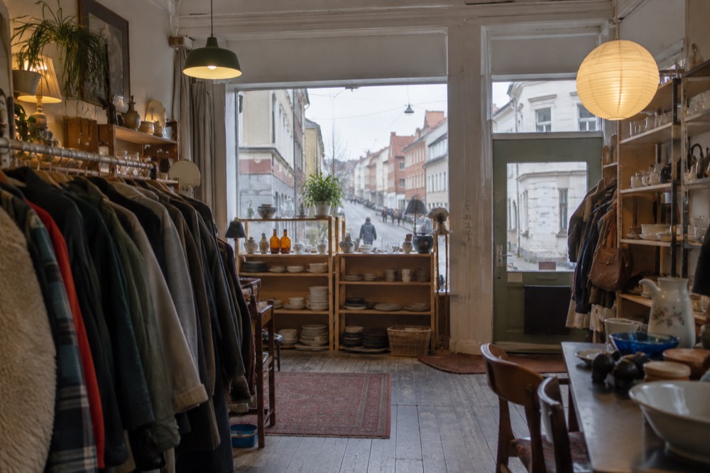 Second-hand shop interior with racks of coats and shelves of household goods
