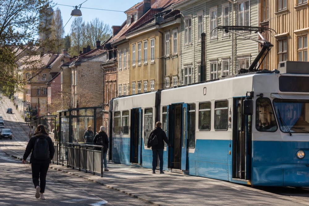 A Gothenburg tram at a stop with wooden houses behind it
