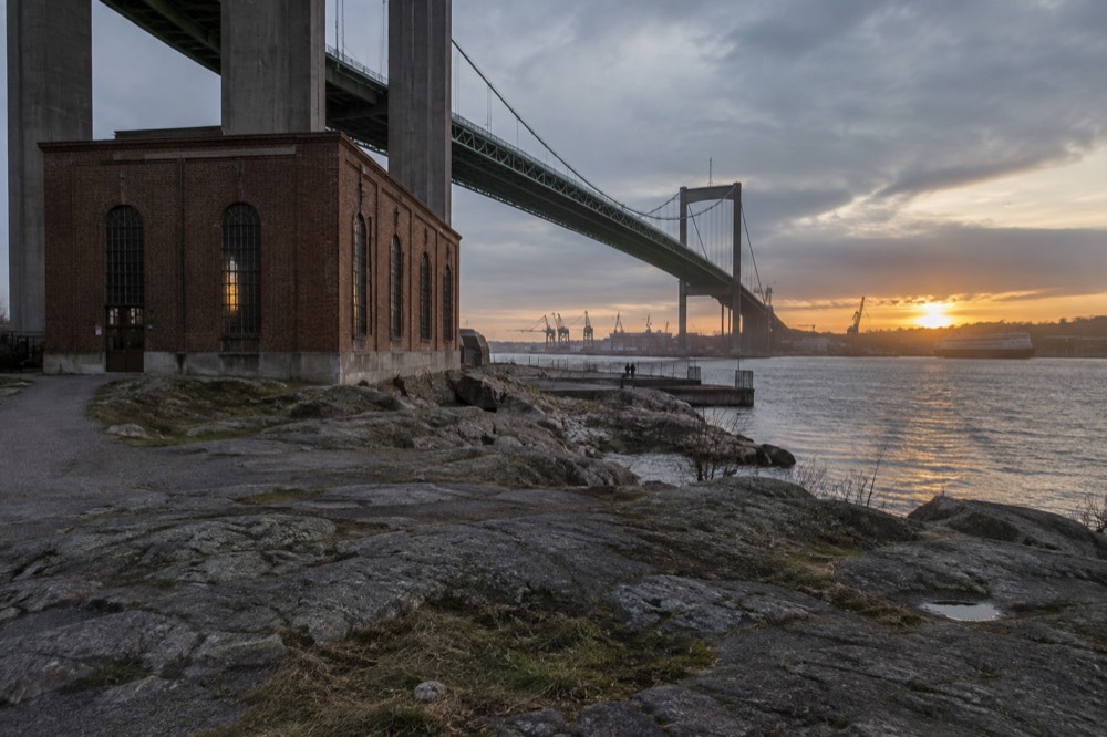 Sunset light on the river mouth with the bridge silhouette and harbour cranes
