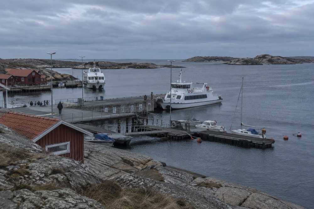 Red wooden boathouses on a rocky granite shoreline facing the open sea