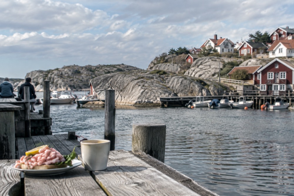 Shrimp sandwich and coffee on a wooden jetty beside a calm ferry harbour