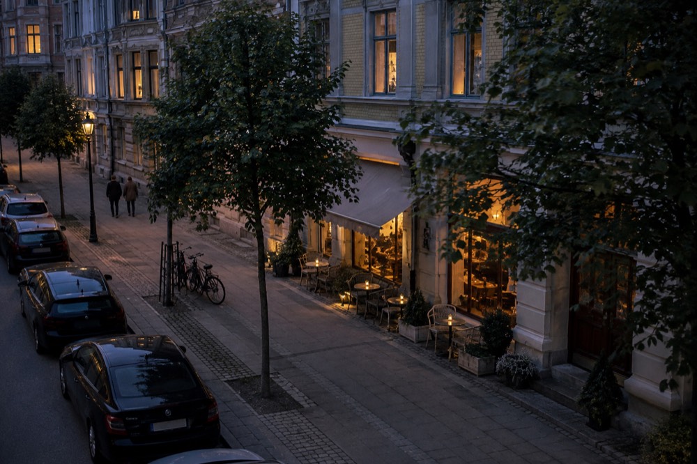 A small neighbourhood restaurant front on an evening street with warm light in the windows