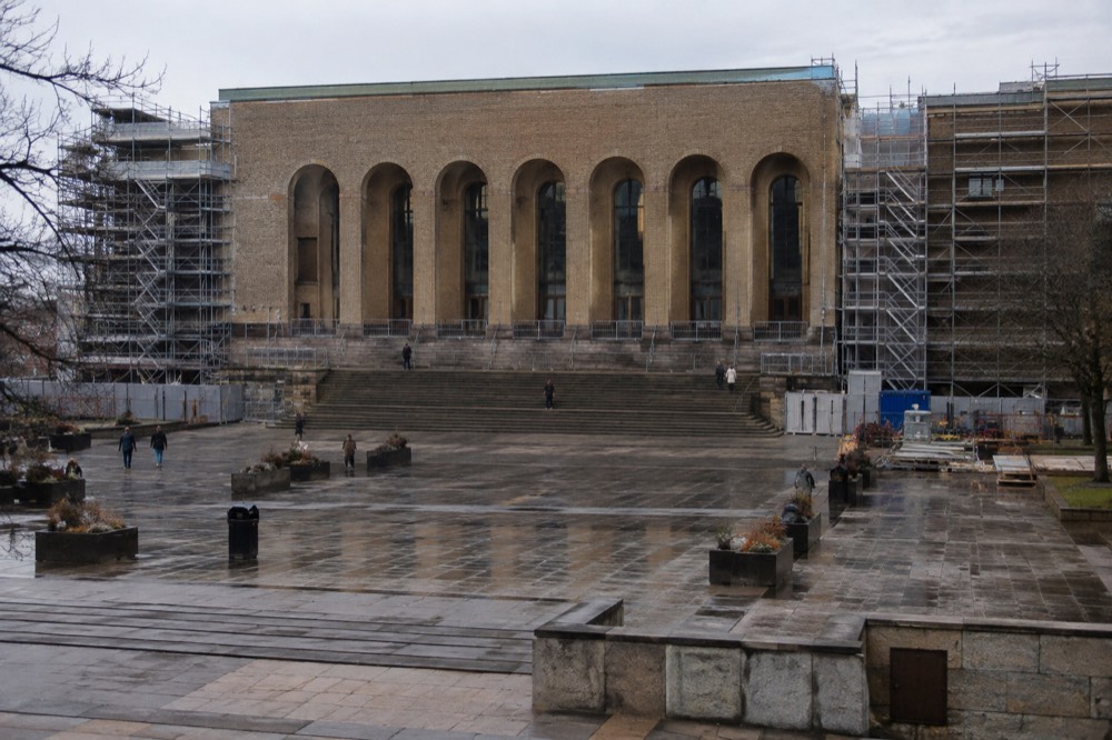 Scaffolding and construction barriers around a stone museum building in a Nordic city