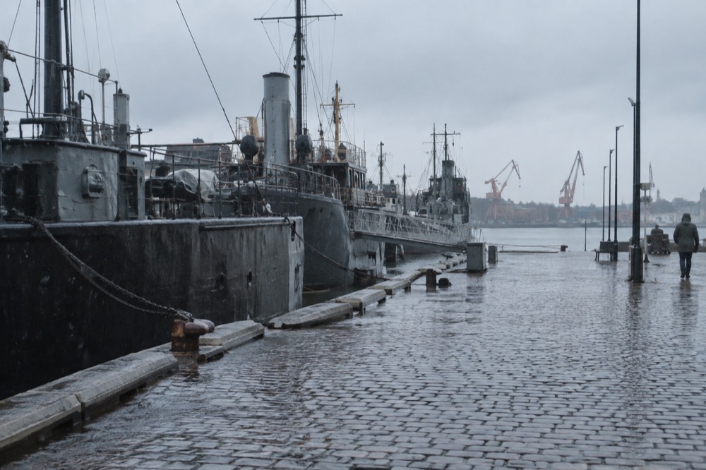 Rain falling on a harbour quay with moored ships and wet cobblestones