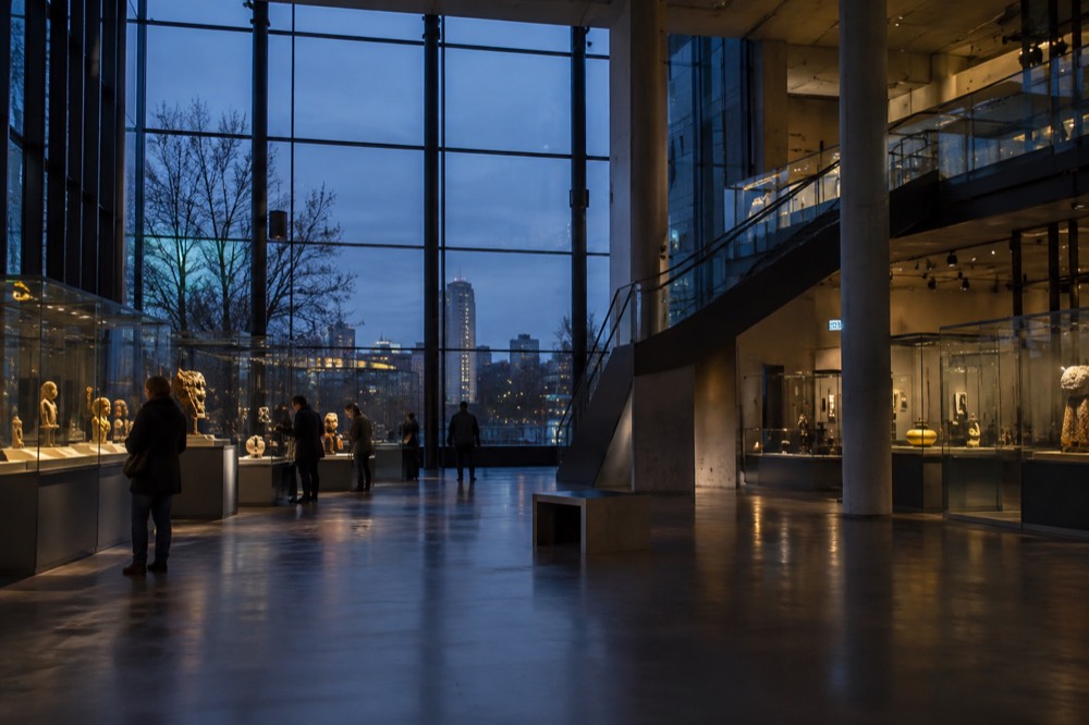 A spacious modern museum gallery with visitors looking at display cases
