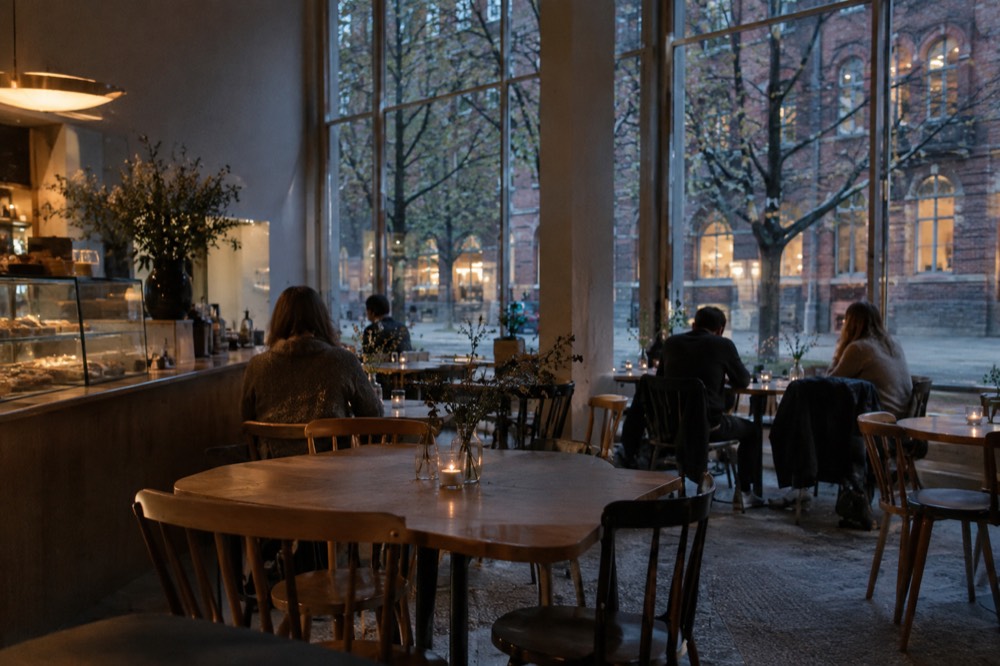 A museum cafe interior with wooden tables and visitors resting between galleries