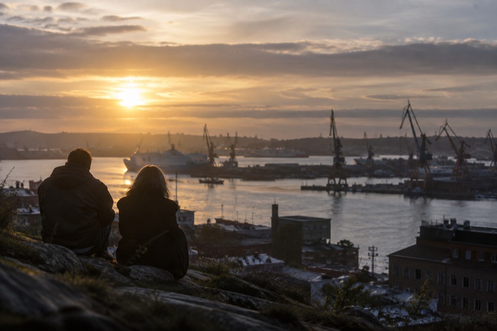 Sunset light over Gothenburg harbour cranes and water from a hilltop