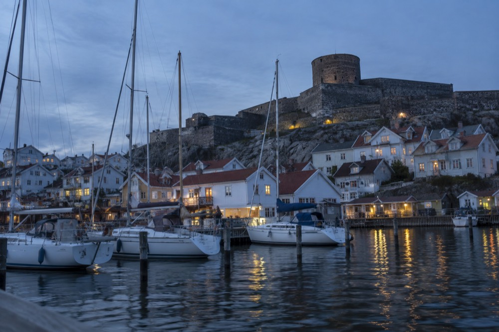 A stone fortress wall above a small harbour crowded with sailing boats