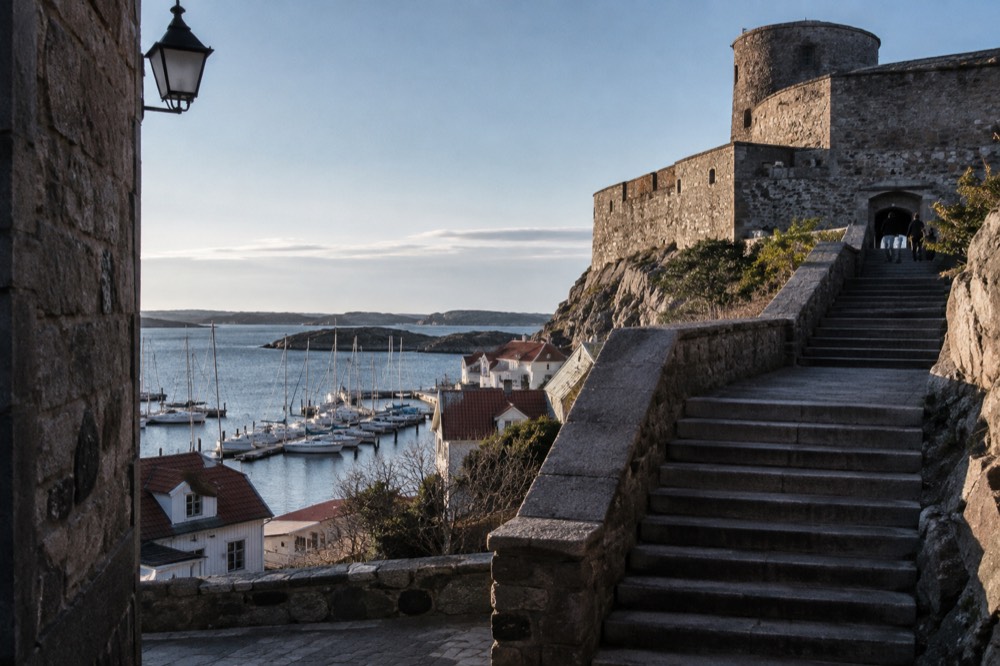 A stone staircase climbing toward a fortress entrance with a view over the sea