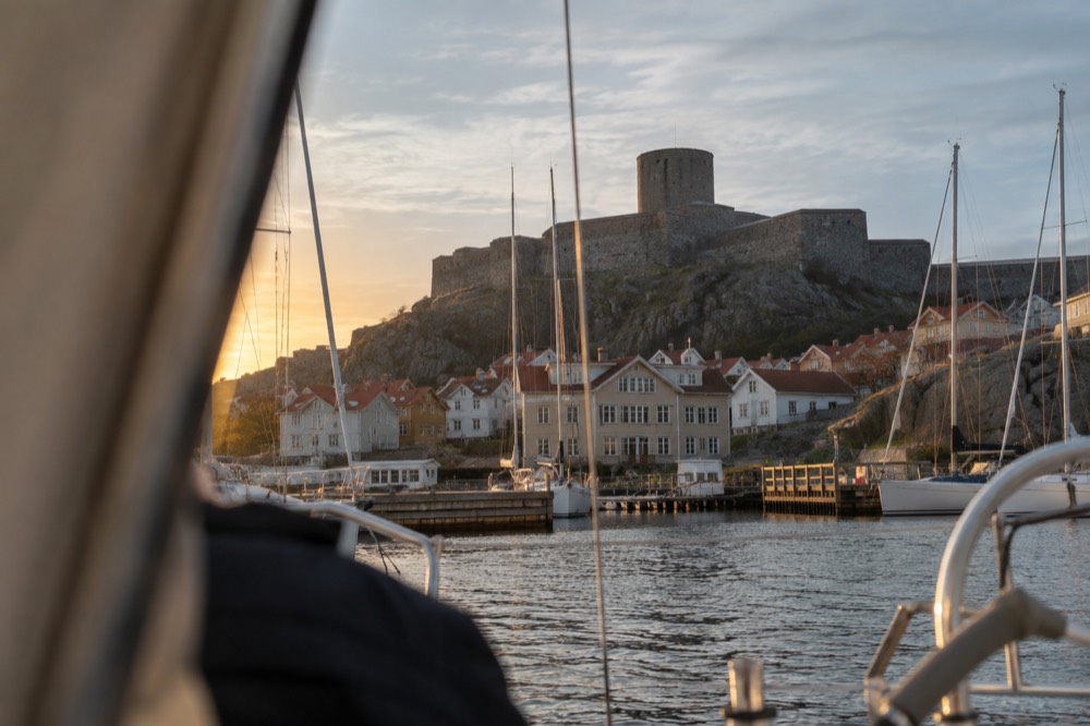 A fortress silhouette on a rocky summit seen from the water at dusk