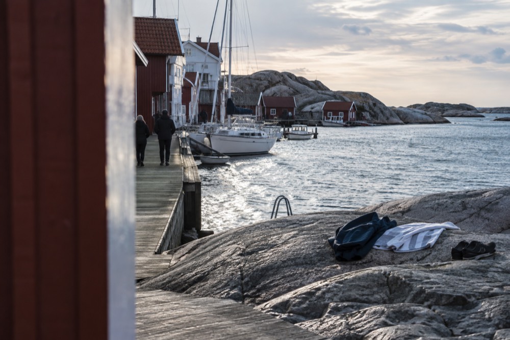 Windbreaker, towel and shoes laid on smooth granite beside the sea
