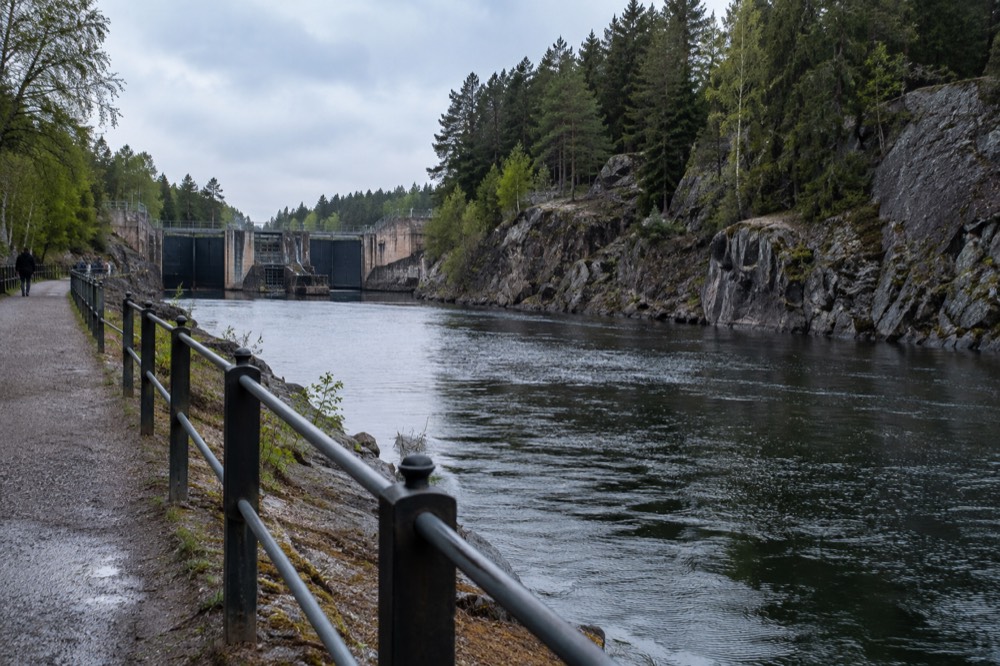 A riverside walking path beside a wide Swedish river with forest on the far bank